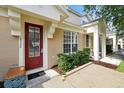 Inviting entrance to townhome with a red front door, bench, and manicured shrubs at 2355 Silver Palm Dr, Kissimmee, FL 34747