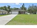 Charming single-story home with a long driveway, attached garage, and welcoming covered front porch at 271 W 11Th St, Chuluota, FL 32766