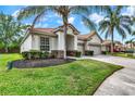Beautifully landscaped single-story house with a three-car garage and brick-paved driveway, set against a sunny sky at 2843 Maria Isabel Ave, Ocoee, FL 34761