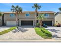 Townhouse exterior showcasing a well-manicured lawn, gray brick driveways, and tropical landscaping at 33 Sea Haven Dr, Ponce Inlet, FL 32127