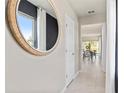 Bright hallway with neutral walls, tile flooring, and a decorative mirror; glimpses of the dining room beyond at 3611 Cambridge Brook Dr, Davenport, FL 33837
