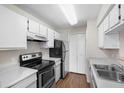Bright kitchen features white cabinets, a stainless steel refrigerator and a black electric range at 4355 Perkinshire Ln # 103, Orlando, FL 32822