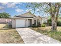 Inviting single-story home boasts a driveway and a well-lit facade, framed by mature tree at 7435 Groveoak Dr, Orlando, FL 32810