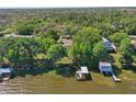 Aerial view of a home surrounded by lush greenery, with a dock and boathouse on the waterfront at 9900 W Lake Marion Rd, Haines City, FL 33844