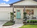 Inviting covered front porch with aqua door, stone steps, manicured shrubs and pavers at 1136 W Harvard St, Orlando, FL 32804
