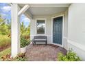 Charming front porch entry featuring tiled flooring, outdoor bench, and well maintained landscaping at 2587 Cliff Way, St Cloud, FL 34771
