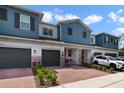 Charming exterior view of two-story townhomes with brick driveway and gray garages at 4839 Jackstaff Way, Oviedo, FL 32765