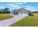 Aerial view of single-story home featuring a three-car garage, paved driveway, and manicured lawn at 6607 Whispering Pines Rd, Orlando, FL 32824