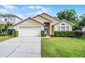 Charming single-story home featuring a well-manicured lawn, two-car garage, and inviting front entrance with arched window at 150 Golfside Cir, Sanford, FL 32773