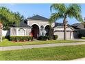 A gray single-story home with a well-manicured lawn and a two-car garage, complimented by lush landscaping at 10827 Lemay Dr, Clermont, FL 34711