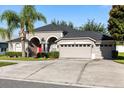 A gray single-story home with a well-manicured lawn and a two-car garage with a long drive way at 10827 Lemay Dr, Clermont, FL 34711