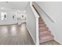 Open-concept living room featuring wood-style flooring and a view into the kitchen, and carpeted stairs at 836 Poppy Ln, Dundee, FL 33838
