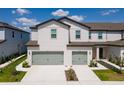 Exterior of a modern townhome featuring a two-car garage and landscaped front yard at 848 Poppy Ln, Dundee, FL 33838