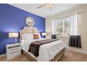 Cozy bedroom with a large window, ceiling fan, and a calming blue accent wall at 8944 Sugar Palm Rd, Kissimmee, FL 34747