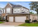 View of home's right side showcasing brick and stone details and a three-car garage at 1638 Swallowtail Ln, Sanford, FL 32771