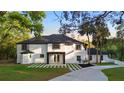 Beautiful home with modern architecture, white stucco, black trim and a well-manicured lawn at 305 Sweetwater Club Cir, Longwood, FL 32779