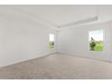 Spacious carpeted bedroom filled with natural light from the two windows and a tray ceiling at 640 Royal Palm Dr, Dundee, FL 33838