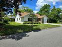 View of a lovely single-story home featuring a well-kept lawn and mature trees in a serene setting at 1016 Monroe Ave, St Cloud, FL 34769