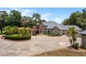 Stunning exterior elevation of a well-manicured home with a circular driveway and water fountain at 11450 Nellie Oaks Bnd, Clermont, FL 34711
