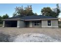 View of an unfinished exterior elevation including an attached garage, windows, and a front door at 13075 Se 35Th Ct, Belleview, FL 34420