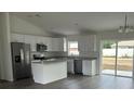 Modern kitchen boasts stainless appliances, a center island, and sliding glass doors leading to the backyard at 13075 Se 35Th Ct, Belleview, FL 34420