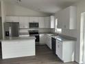 Bright kitchen with white cabinets, stainless steel appliances, an island, and granite countertops at 13075 Se 35Th Ct, Belleview, FL 34420