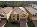 An aerial view of a tan two-story house featuring a tile roof, brick driveway, and a well-maintained lawn at 8892 Bengal Ct, Kissimmee, FL 34747