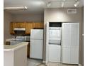 Bright kitchen with white appliances, wooden cabinets, and stacked washer and dryer at 9021 Lee Vista Blvd # 1707, Orlando, FL 32829