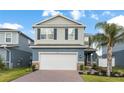 Two-story home with a brick driveway, attached garage, and tropical landscaping at 903 Sydney St, Davenport, FL 33837