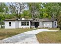 A single-story home features a crisp white exterior with black accents and a freshly poured concrete driveway at 239 S Lake Cortez Dr, Apopka, FL 32703