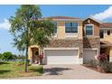 Charming two-story townhome showcasing a brick-accented facade, attached garage, and picturesque landscaping at 1969 Portofino Meadows Blvd, Orlando, FL 32824