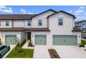 Modern two-story townhomes with a well-manicured lawn, green garage doors, and a light-colored facade at 824 Poppy Ln, Dundee, FL 33838