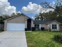 Single story brick home with a well-maintained lawn and a two car garage at 1563 W Finland Dr, Deltona, FL 32725