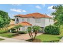 Two-story home featuring a tile roof, a brick driveway, palm trees, and a two-car gray garage at 2107 Rickover Pl, Winter Garden, FL 34787