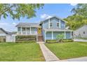 Charming blue two-story home featuring a yellow door, a welcoming front porch, and lush landscaping at 417 Barclay Ave, Altamonte Springs, FL 32701