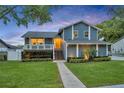 Charming blue two-story home featuring a yellow door, a welcoming front porch, and lush landscaping at dusk at 417 Barclay Ave, Altamonte Springs, FL 32701
