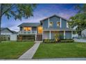 Charming blue two-story home featuring a yellow door, a welcoming front porch, and lush landscaping at dusk at 417 Barclay Ave, Altamonte Springs, FL 32701