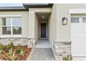 Inviting front entrance with stone accents, a covered porch, and a well-lit pathway to a modern black front door at 1755 Waterview Dr, Leesburg, FL 34748