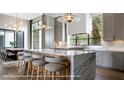 A modern kitchen boasts a marble island with seating and designer pendant lighting at 1910 Glencoe Rd, Winter Park, FL 32789
