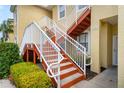 Close-up of condo building stairs, showcasing red stairs, white railings, and well-maintained landscaping at 5201 Lake Marion Golf Resort # 5201, Kissimmee, FL 34759