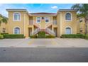Attractive two-story condo with a yellow exterior, red tile roof, white stair railings, and well-maintained landscaping at 5201 Lake Marion Golf Resort # 5201, Kissimmee, FL 34759