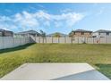 Spacious backyard with lush green grass, a concrete pad, and white fencing at 830 Turner Ln, Winter Haven, FL 33881