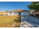Inviting single-story home featuring a well-manicured lawn and a two-car garage at 104 Birmingham Dr, Kissimmee, FL 34758