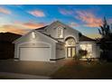 Charming single-Gathering home with a gray exterior, well-manicured lawn, and a two-car garage at dusk at 12557 Crayford Ave, Orlando, FL 32837