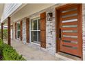 Close-up of the front entrance showcasing a modern wood door, stylish light fixture, and whitewashed brick detail at 201 Cedarwood Dr, Maitland, FL 32751