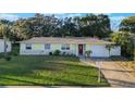 Well-kept one-story home featuring an attached garage, red door, and manicured lawn with landscaping at 2070 Keyes Ln, Deltona, FL 32738
