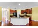 Spacious kitchen boasts cherry wood cabinets, granite countertops, a center island, and modern black appliances at 2081 The Oaks Blvd, Kissimmee, FL 34746