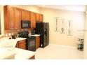 Kitchen features cherry cabinets, black appliances, tile backsplash, and tile flooring at 6453 Alcalde Ct # 104, Orlando, FL 32835