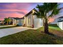Exterior home showcasing a tropical palm, fresh landscaping, long driveway, and warm lighting at 804 Colville Dr, Kissimmee, FL 34759
