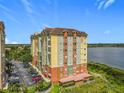 Lakefront condo building with colorful facade, tile roof, ample parking, and lush landscaping at 8743 S The Esplanade # 18, Orlando, FL 32836